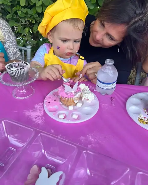 Child decorating a cupcake at a pink party table