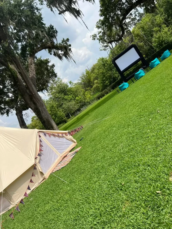 A tent with the Ultimate Movie Night Setup Training Package - Transform Your Events set up in a grassy area.