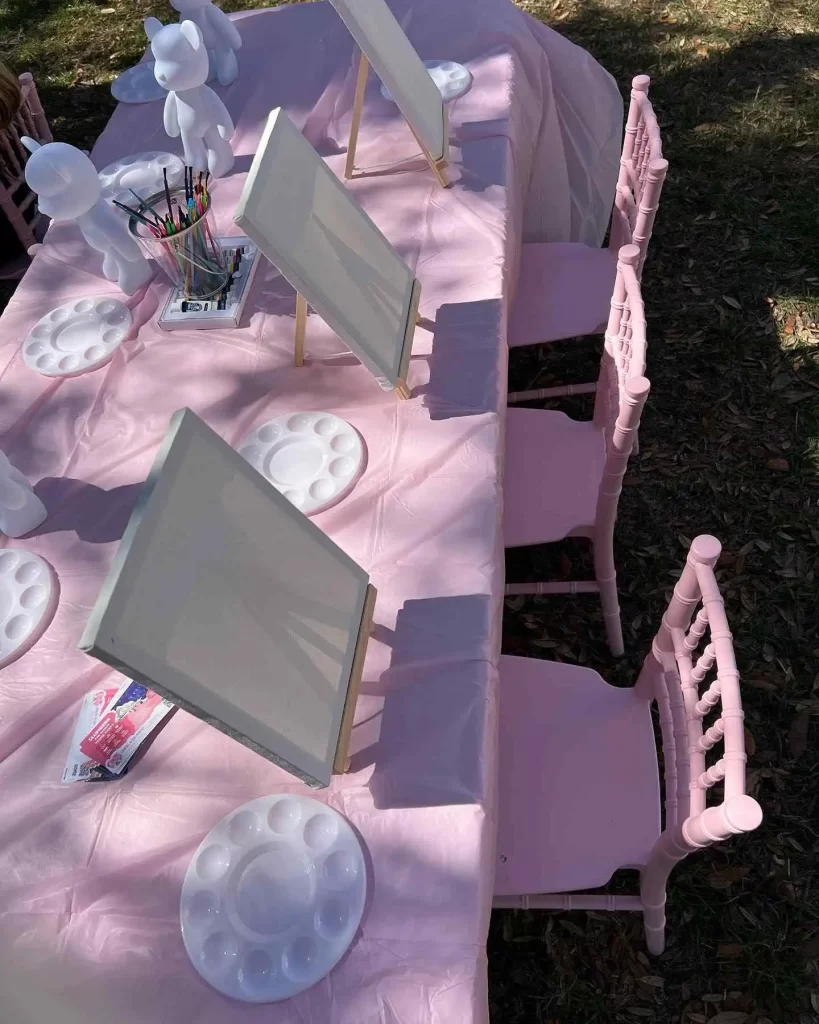 A table set up for a Ultimate Movie Night Setup Training Package - Transform Your Events party with pink chairs.