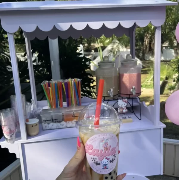 A person holding up a cup of Custom Party Labels at a party.