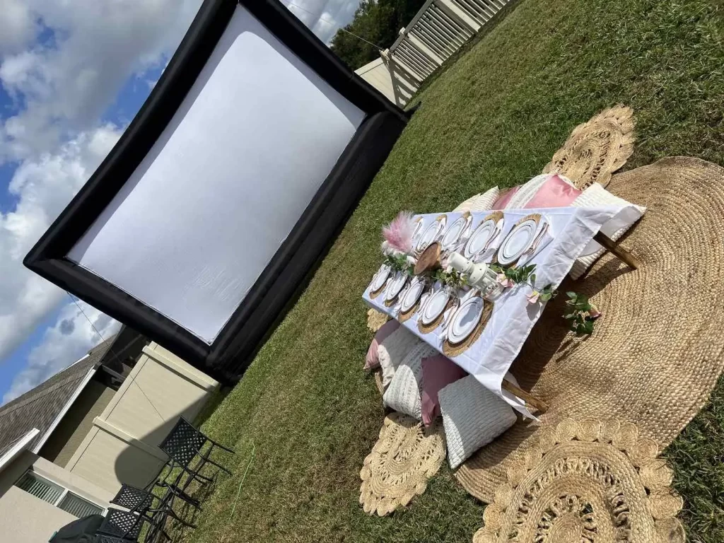 An Transform Your Events, featuring a backyard movie set up with a table and chairs.