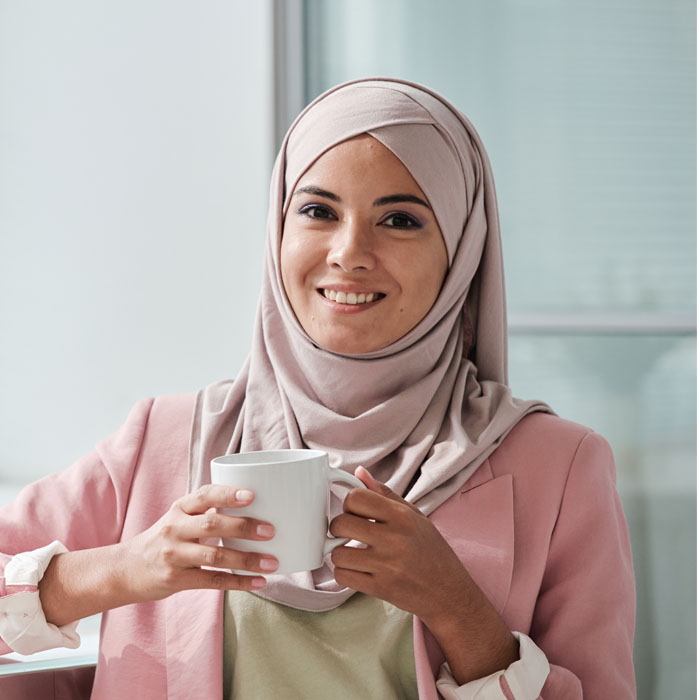 A muslim woman in hijab holding a cup of coffee.
